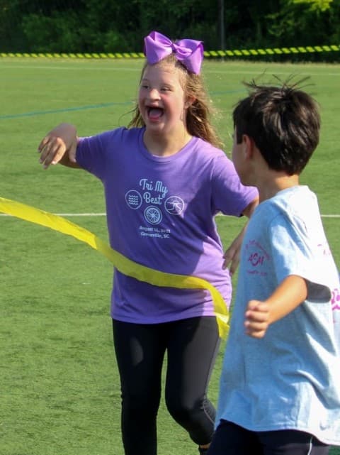 tri my best participant Addison crosses finishline with a smile