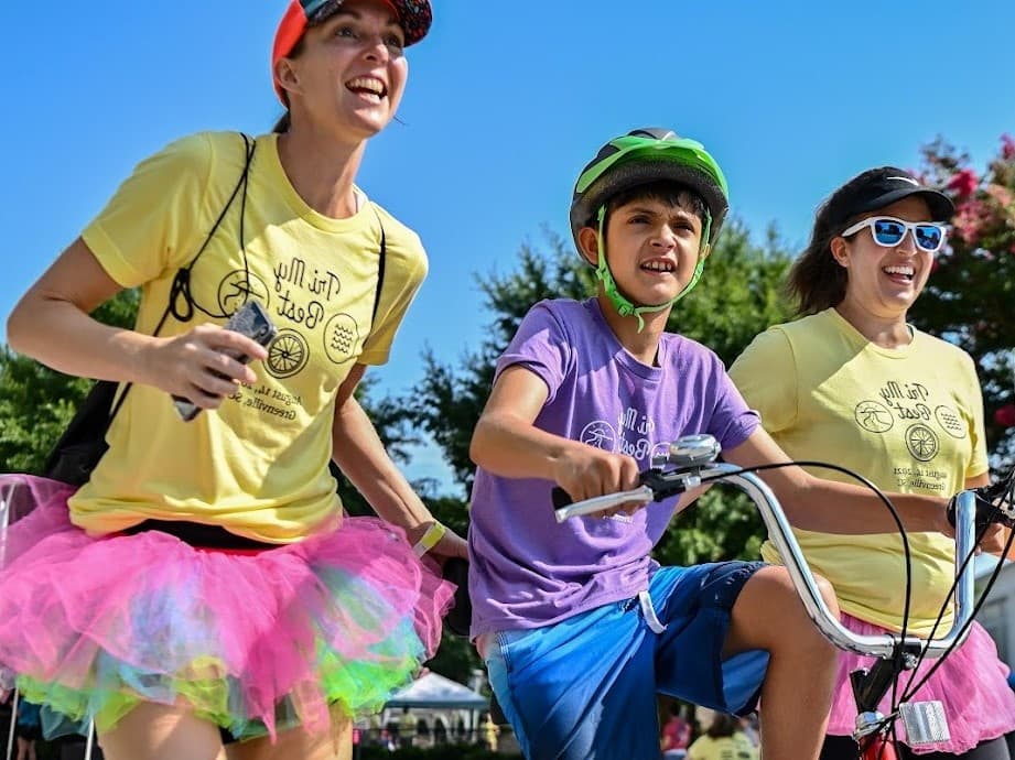 triathalon biker helped by buddies in coloful tutus