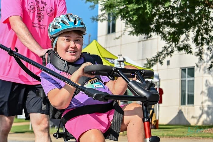 Tri My Best biker harnessed into adaptive bike smiles at camera