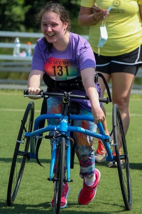 tri my best biker smiles at camera from adaptive bike