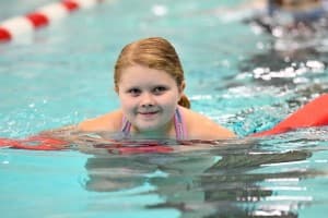 tri my best swimmer with pink pool noodle smiles at the camera