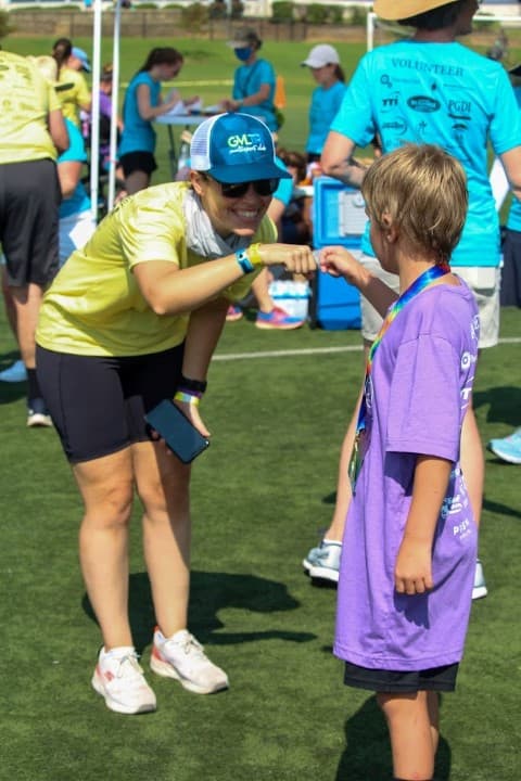 tri my best volunteer gives participant fist bump after race